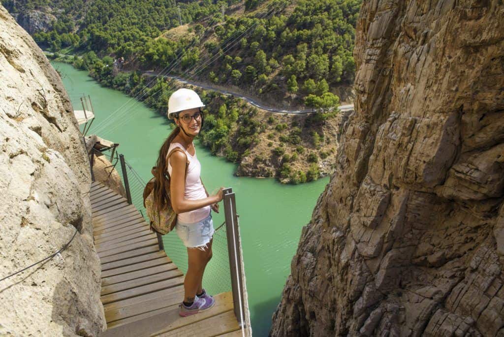 Woman hiking along a canyon trail overlooking a green river in Malaga, Spain.