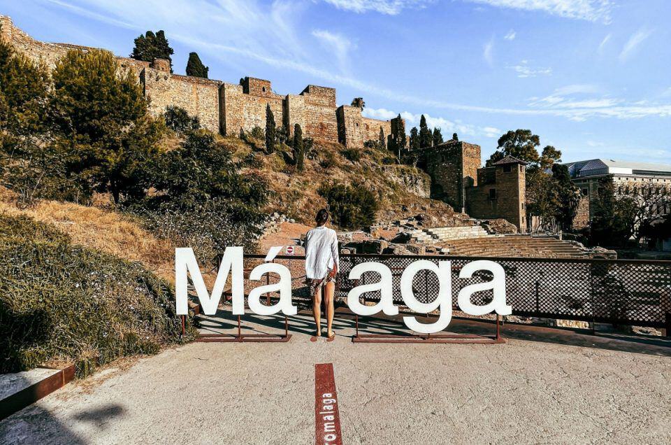 Scenic view of Malaga's historic city walls and a tourist exploring the site.