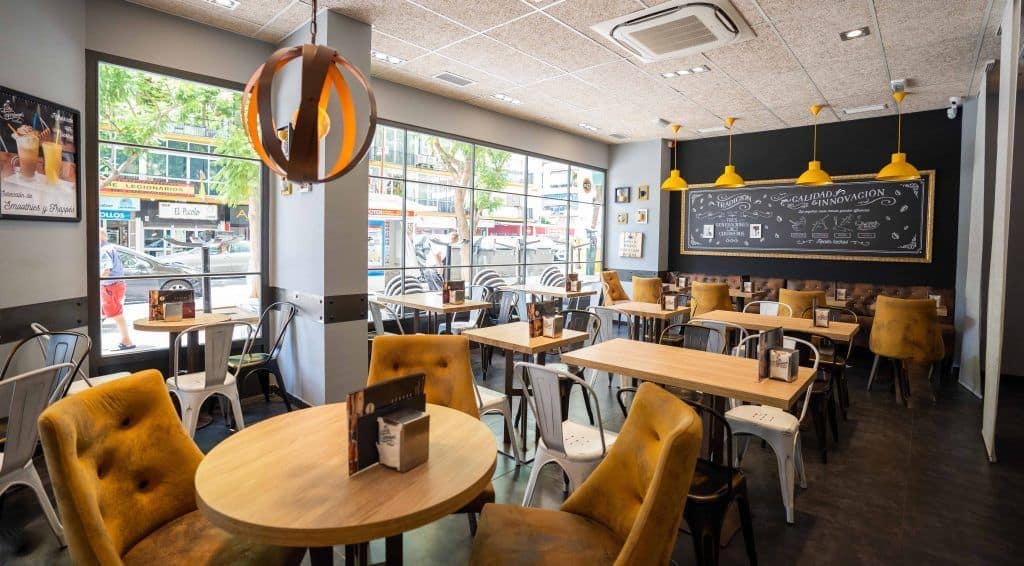 Bright interior of a Malaga breakfast cafe with comfortable seating and large windows.