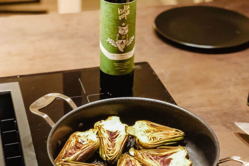 Artichokes roasting in a skillet on a stovetop for a delicious dish.