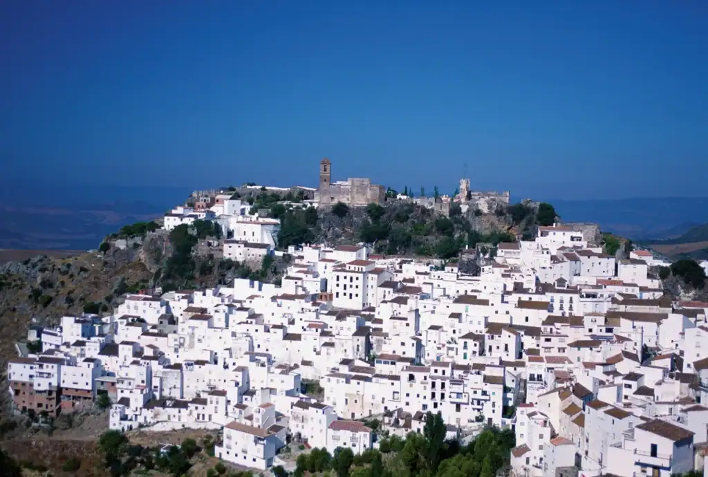 Scenic view of whitewashed villages in Andalusia with historic castle and lush greenery.