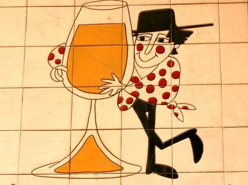 Iconic Málaga bar with cheerful mural of a character holding a large glass of wine.